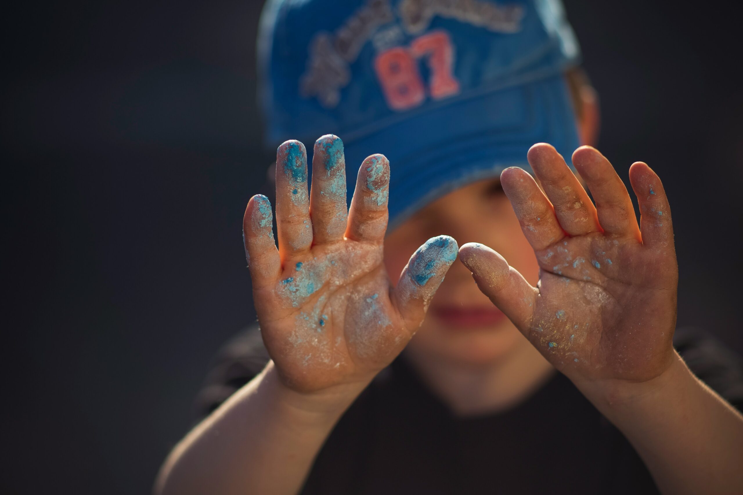 person in blue and white shirt covering face with hands